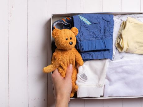 Kinderkleidung und Teddy in Schachtel